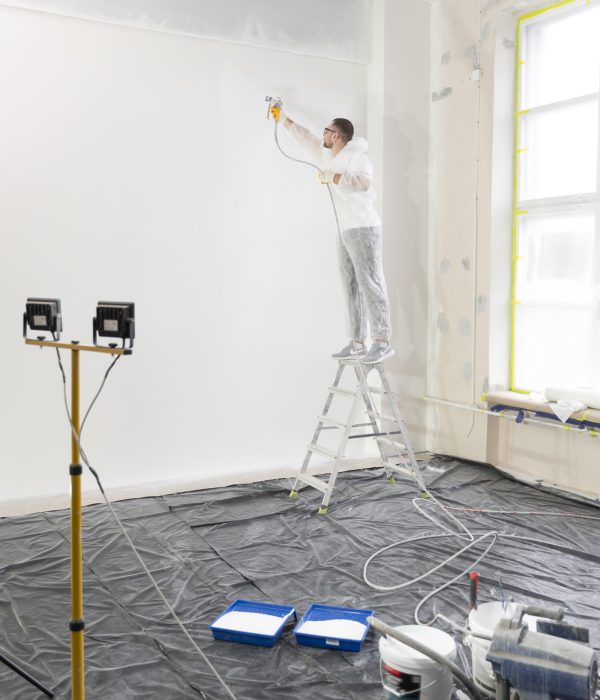 worker-painting-wall-ladder-full-shot